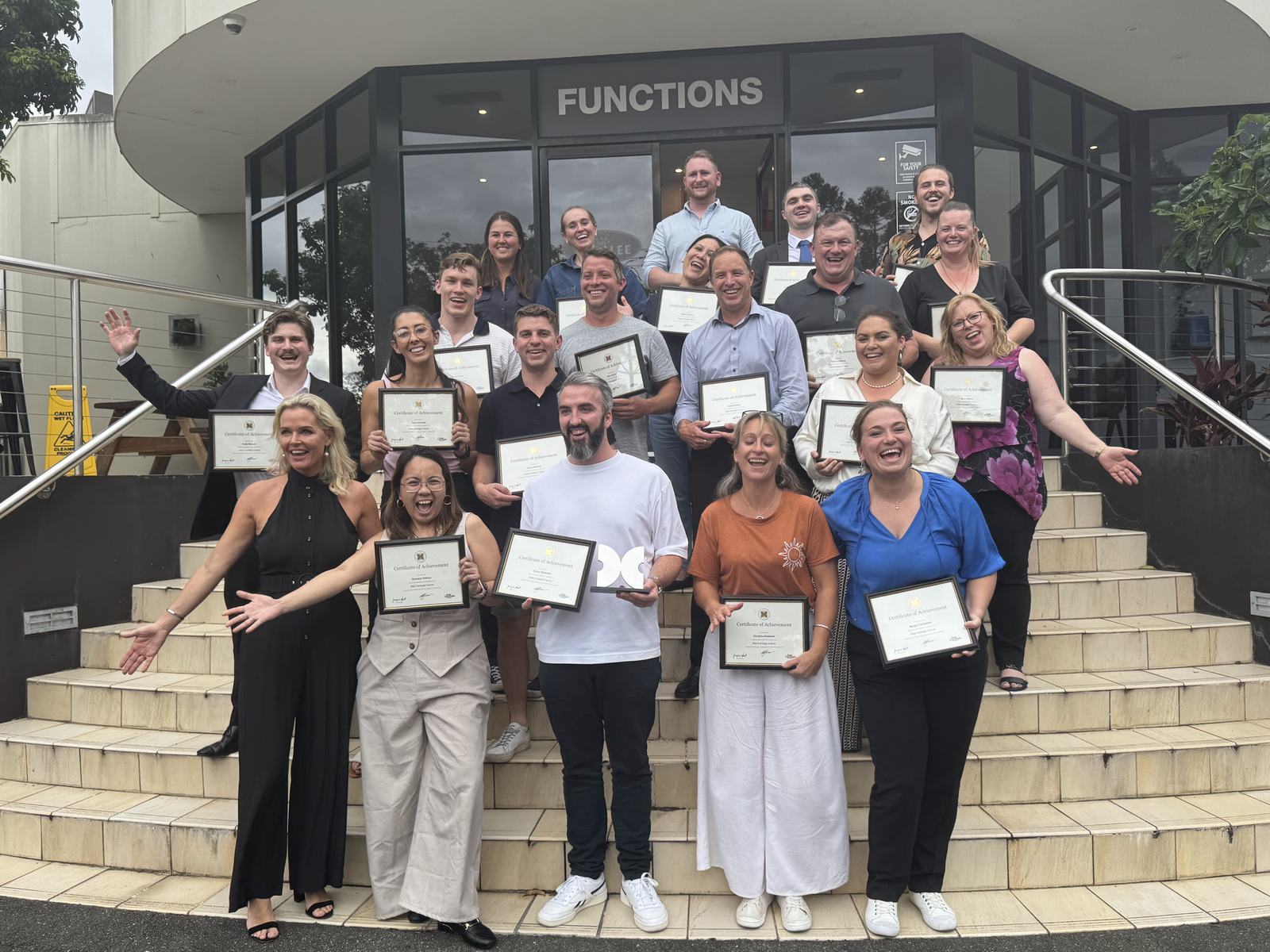 Graduates holding their Dale Carnegie certificates on the front steps of the Jindalee function centre