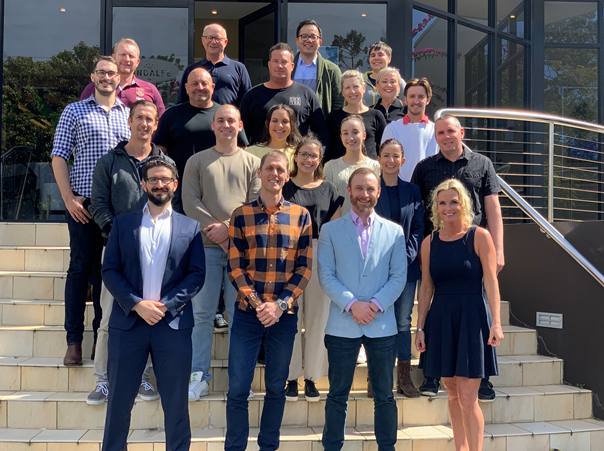 A smiling Dale Carnegie class standing together on a flight of outdoor steps