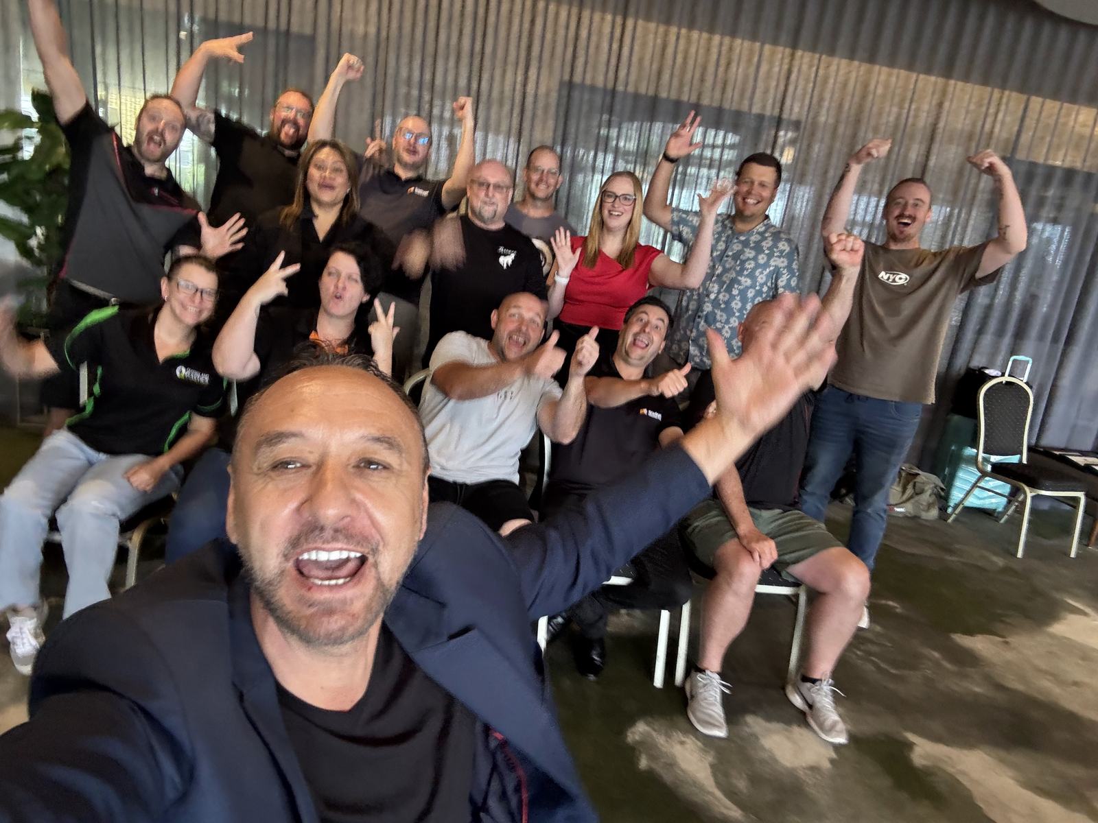 A seated class raising their arms and cheering during a Dale Carnegie session