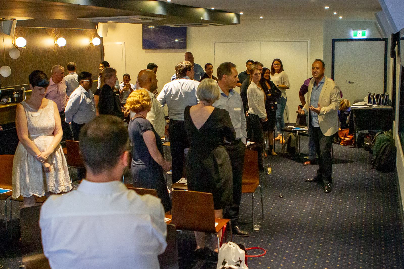 Participants standing in pairs and small groups while William Farmer guides an interactive exercise